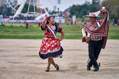 Şilili huasolar gibi giyinmiş, açık havada neşeyle dans eden genç bir çiftin portresi. Geleneksel Şili dansı. Şili gelenekleri, kutlamalar.
