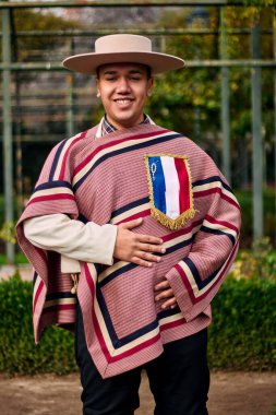 Şilili bir huaso gibi giyinmiş gülümseyen, neşeli bir gencin portresi geleneksel bir Şili dansı olan cueca dansını kutluyor ve poz veriyor. Şili gelenekleri, kutlamalar ve kültür.