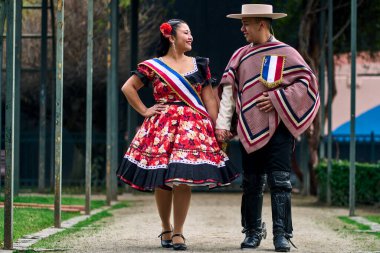 Şilili huasolar gibi giyinmiş, birbirlerine bakıp geleneksel bir Şili dansı olan cueca dansı için romantik poz veren genç bir çiftin portresi. Şili gelenekleri, kutlamalar ve kültür.