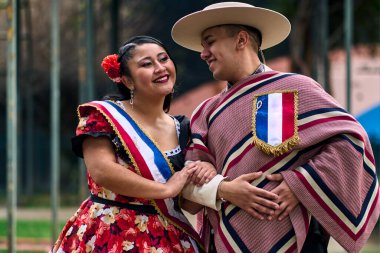 Şilili huasolar gibi giyinmiş, birbirlerine bakıp geleneksel bir Şili dansı olan cueca dansı için romantik poz veren genç bir çiftin portresi. Şili gelenekleri, kutlamalar ve kültür.