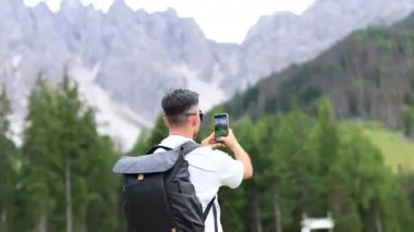 Bir gezgin, yemyeşil güzelliklerle çevrili nefes kesici dağların çarpıcı bir fotoğrafını çeker.