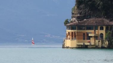 Güzel ve sakin bir göl kenarındaki villa manzarası sakin ve sakin sularda yüzen bir teknenin yanında.