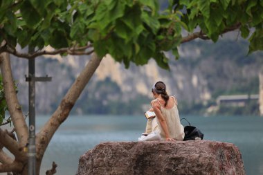 Huzurlu bir kadın, sakin, güzel bir göl kenarında, nefes kesici, canlı doğal güzelliklerle çevrili.