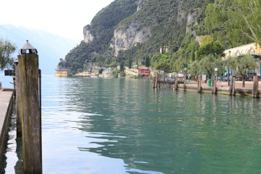 Huzurlu bir göl manzarası canlı yeşil sular görkemli dağlar ve ilginç büyüleyici binalar sergiliyor.