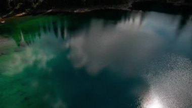 Sakin bir gölün çarpıcı manzarası bulutları ve yeşil ağaçları sonbahar uyumu içinde yansıtıyor. İtalya. Dolomitler. Carezza Gölü
