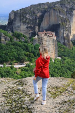 Kırmızı kazaklı kadın Yunanistan 'daki Meteora manastırı yakınlarındaki dağlarda doğanın tadını çıkarıyor. Yüksek kalite fotoğraf