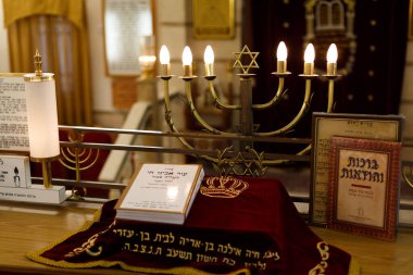 Güzel düzenlenmiş bir menorah, Tevrat parşömeni ve sakin bir sinagogda dekoratif kumaş, zengin gelenekler sergiliyor.