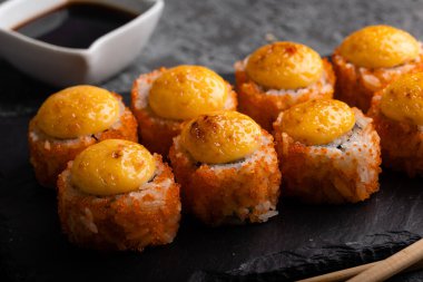 Taze suşi hazır. Suşi California 'yı peynirle yuvarlıyor. Siyah arka planda suşi, yemek çubukları, wasabi, soya. Üst görünüm.