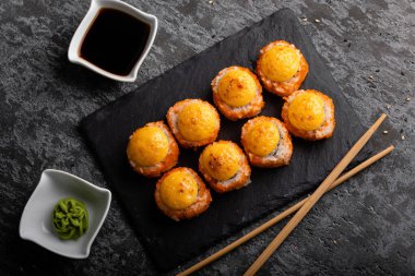 Taze suşi hazır. Suşi California 'yı peynirle yuvarlıyor. Siyah arka planda suşi, yemek çubukları, wasabi, soya. Üst görünüm.