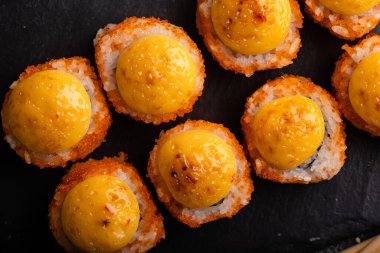 Taze suşi hazır. Suşi California 'yı peynirle yuvarlıyor. Siyah arka planda suşi, yemek çubukları, wasabi, soya. Üst görünüm.