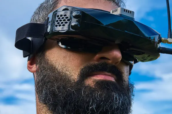 FPV insansız hava aracı sakallı çekici erkek pilot açık hava mavi gökyüzünü kapatın. Arap erkek helikopter vr operatörü VR gözlüklü uçak akademisi eğitim sahası arıyor