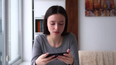 Genç bir kadın tamamen meşgul, kapalı mekanda akıllı telefonuyla cep telefonu oyunu oynuyor. Macera, bulmaca, aksiyon, strateji, simülasyon, atari ve rol yapma gibi çeşitli oyun türlerini sever.