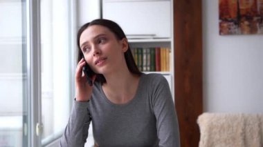 Genç bir kadın sıcak bir şekilde selamlar ve akıllı telefonuyla kısa bir konuşma yapar ve neşeli bir veda ile sona erer. Kapalı alan ayarları, gündelik iletişim, bağlantı ve dijital konseptler için mükemmel.