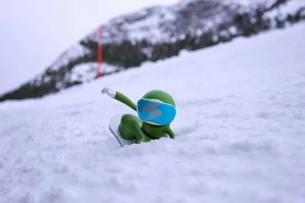 Kış aktiviteleri konseptinde güvenlik kuralları. Canlı, yeşil bir snowboardcu mavi gözlükler takıyor taze kar üzerinde süzülüyor, resim gibi bir dağ ortamında aksiyon ve enerji sergiliyor.