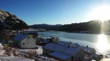 Göz kamaştırıcı bir dağ manzarası olan kuzey karlı bir kasabayı çeken panoramik bir video. Güneş ışıl ışıl parlıyor, güzel mercek parlamaları yaratıyor. Deniz fiyortu, kayalık sahil ve evler...