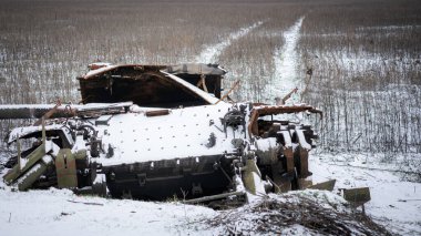 Rus ordusunun patlamış tankı karla kaplı bir tarlanın arka planına karşı. Arka planda, alanda tank hareketi izleri var.
