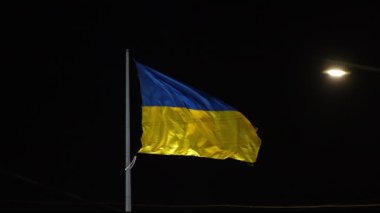 Güzel bir Ukrayna bayrağının gece gökyüzüne karşı gururla dalgalanan bir fenerin sıcak bir parıltısıyla görüntüsü. Ukrayna 'nın yıldızların altındaki dayanıklılığının ve birliğinin bir sembolü..