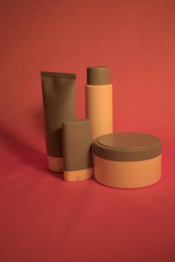 Pembe arka planda kozmetik ürünleri. Kutu, şişe, sopa ve krema var..