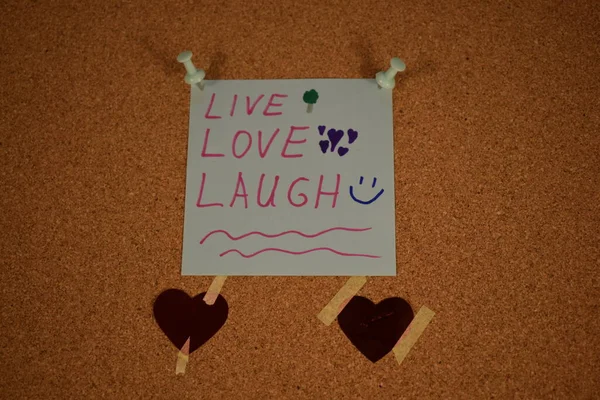 Live, Love, Laugh message on a paper on a pinboard