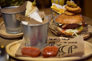 Vegan burger in a restaurant with onion rings on top and french fries on side
