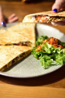 Detail of a vegan burrito and quesadilla with avocado on a fancy plates in a restaurant