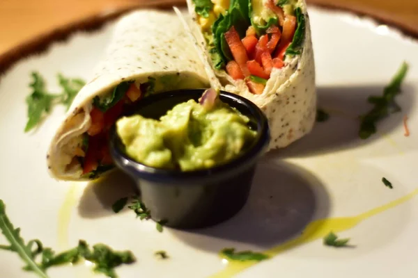 Detail of a vegan burrito and quesadilla with avocado on a fancy plates in a restaurant