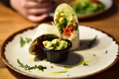 Detail of a vegan burrito and quesadilla with avocado on a fancy plates in a restaurant