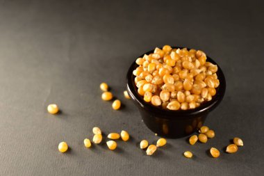 Corn seeds in a black bowl on a black background