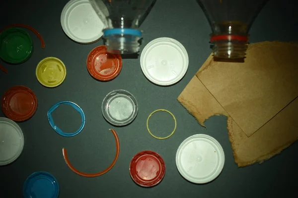 Plastic bottle caps, bottles and cardboard on a gray background. Concept of plastic waste problem and recycling.