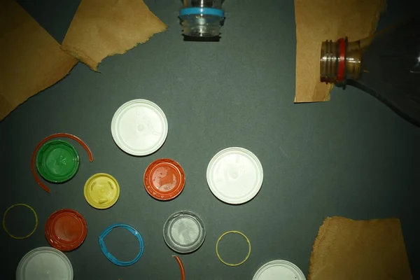 Plastic bottle caps, bottles and cardboard on a gray background. Concept of plastic waste problem and recycling.