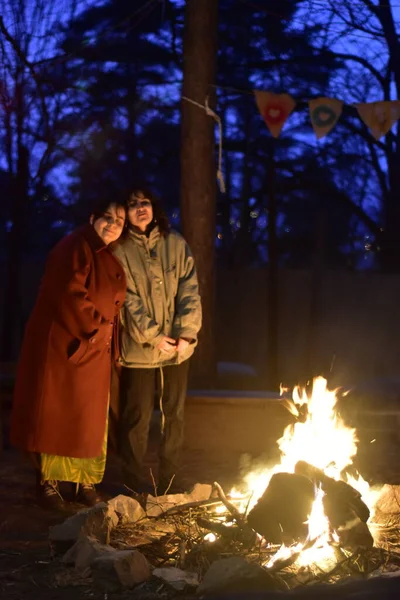 Two female friends near campfire on a cold night