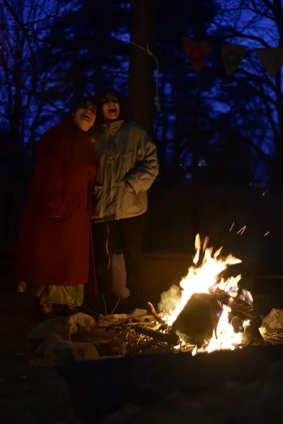 Two female friends near campfire on a cold night