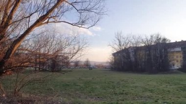 Two people sitting on a field on public park near brutalist styled buildings on a sunny winter evening
