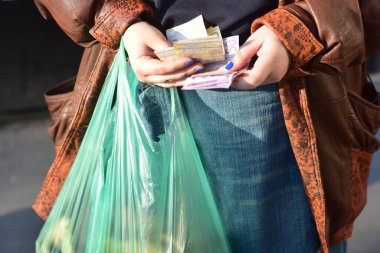 A woman counting Serbian dinars with a plastic bag in her hands