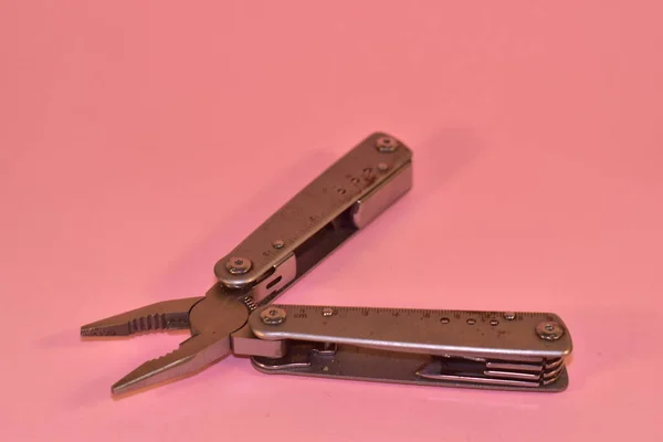 Multi tool pliers on a pink background