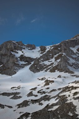 Eski model çift koltuklu asansör. Baharda kar altında bir kayak merkezinde. 