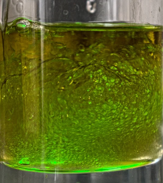 绿色激光射中充满含油液体的玻璃杯的抽象形式 — 图库照片