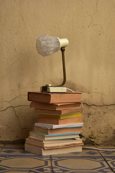 Bir yığın eski kitap ve bir lamba.