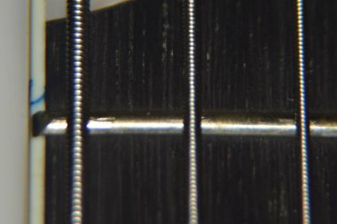 Bas gitar tellerini kapat. Enstrümanın aşırı makro çekimi kalın, bas gitarın metal telleri.