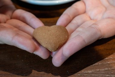 Kalp şeklinde bisküvi ellerde ve kahvede