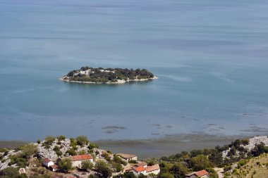 Skadar Gölü panoramasında bir ada. Güneşli ve bulutlu yaz seyahatleri ve tatil fotoğrafçılığı. Güzel arkaplan manzarası.