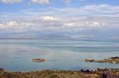 Skadar Gölü panoramasında bir ada. Güneşli ve bulutlu yaz seyahatleri ve tatil fotoğrafçılığı. Güzel arkaplan manzarası.