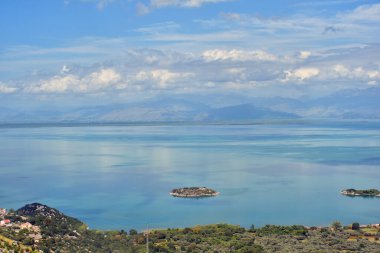 Skadar Gölü panoramasında bir ada. Güneşli ve bulutlu yaz seyahatleri ve tatil fotoğrafçılığı. Güzel arkaplan manzarası.