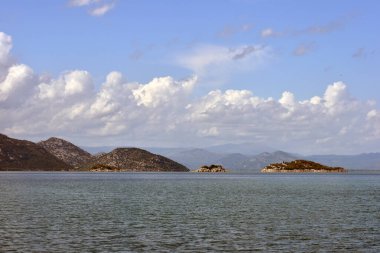 Güneşli ve bulutlu bir günde Skadar Gölü panoraması. Karadağ 'ın vahşi güzelliğinin fotokopi alanının olduğu güzel bir arka plan fotoğrafı. Yazın göl manzarası. 