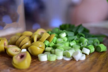 Tahta tabakta doğranmış taze soğan ve zeytin. Yemek fotoğrafçılığı.