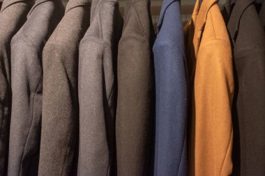 Elbise mağazasındaki askılarda asılı takım elbiseler.