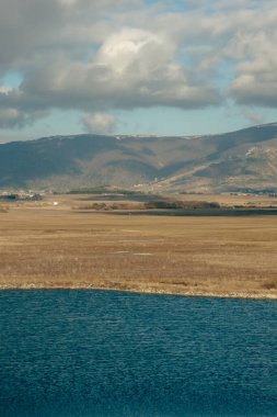 Düz arazide nehir, göl ve dağlar manzarası