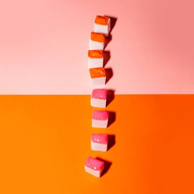 Turuncu ve pembe arka planda renkli şeker küpleri. Asgari yaratıcı kavram. 