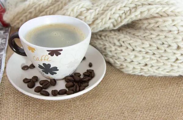 A cup of coffee with some coffee beans around it. Morning concept.