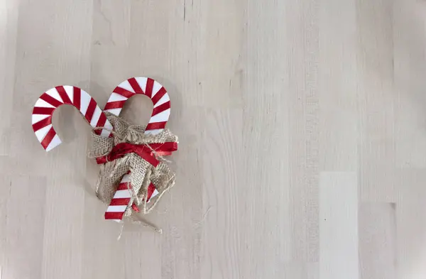Two decorative candy canes over a wooden table. Christmas background, copy space.